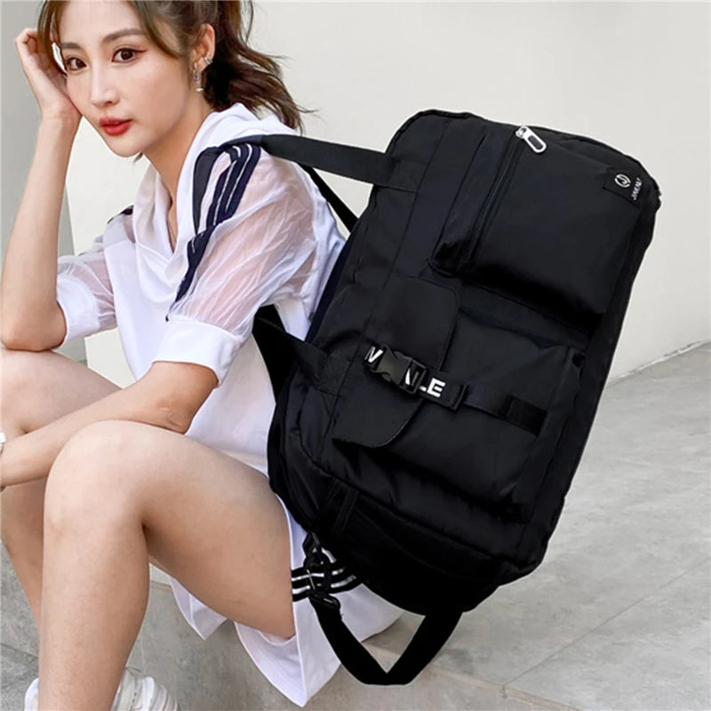 Black women's travel handbag with multiple pockets and adjustable straps carried by woman in casual outfit