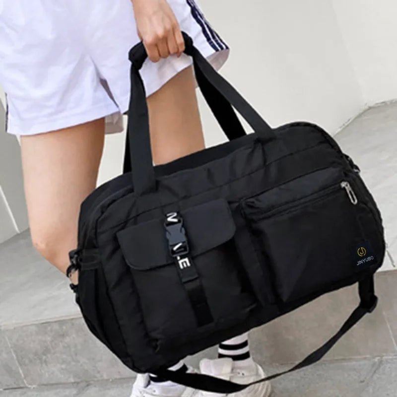 Black women's travel handbag held by person wearing white shorts and sneakers