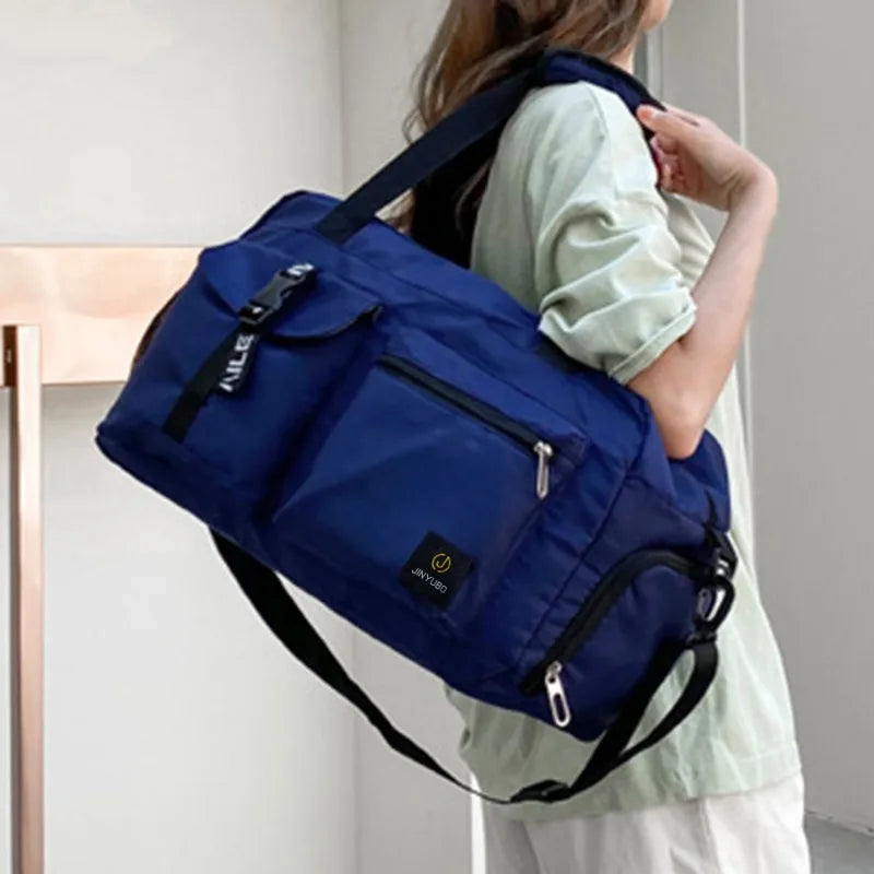 Navy blue women's travel handbag with multiple zippered pockets carried on shoulder