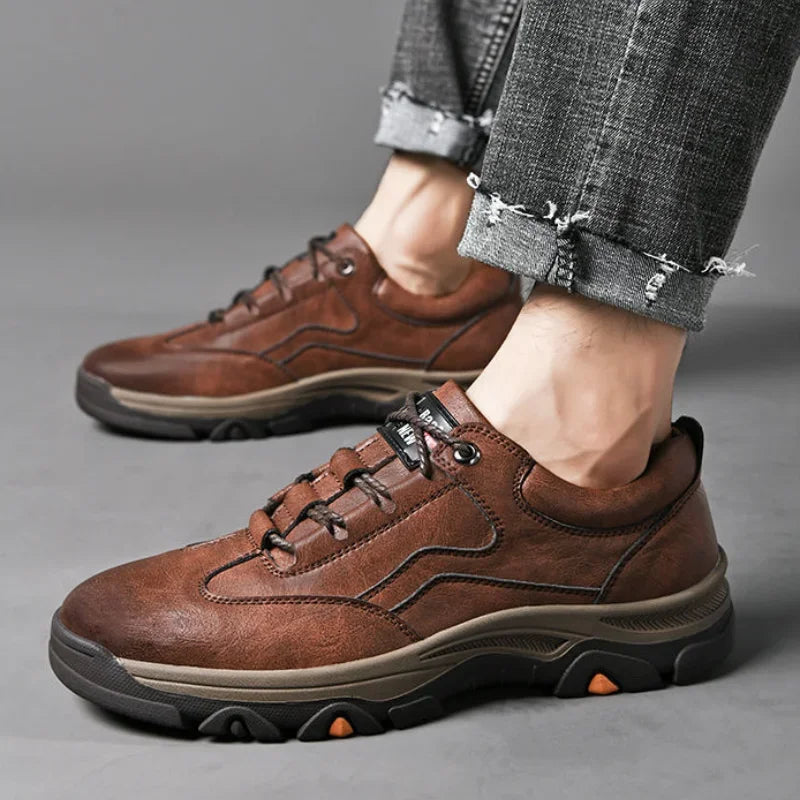 Men's casual outdoor sneakers in brown leather with black and orange rugged sole on feet